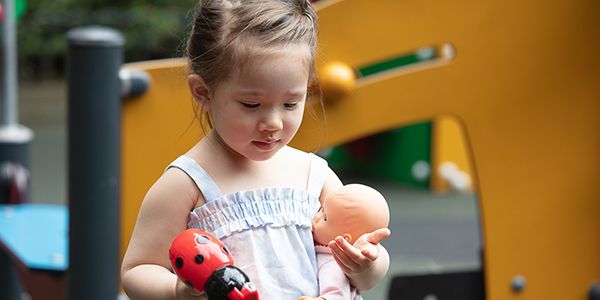 Young girl holding a doll and ladybug toy